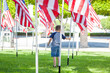 A young boy wanders amidst a field of American flags