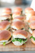 Golden mini burgers with arugula on a wooden serving tray