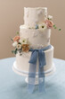 Three Tiered Wedding Cake With Floral Design and Blue Ribbon
