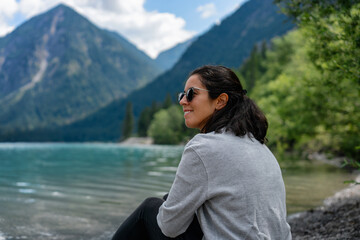 Woman looking to the side with a lake and mountains on the background