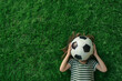 © ink drop - Overhead view of a child laying on green grass holding a soccer football ball