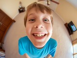Fototapeta  - Fisheye lens view of a smiling boy in a blue shirt with a humorous, exaggerated expression.