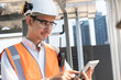 Portrait Asia male engineer in protective workwear is performing a conducts system check with use tablet computer at rooftop building	