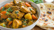 Savory jamaican curry chicken with soft roti bread and fresh herbs served on a rustic wooden table