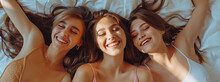 Top View Of Three Beautiful Young Women Laying On The Bed, Smiling And Pointing To Their Faces With Fingers, Beautiful Face Skin And Hair, Spa Day, Natural Light, High Resolution Photography In The St