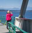 Woman taking photos of distant mountains using a smartphone on the ferry. Seattle. USA. Vertical format.