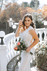 Wall Mural - A woman in a wedding dress is holding a bouquet of flowers. The flowers are pink and white, and the woman is standing on a white railing. Concept of elegance and romance