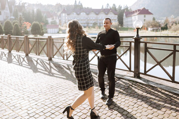 Wall Mural - A man and woman are dancing on a brick walkway. The man is holding the woman's hand