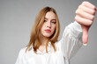 © fotofabrika - Young Woman in White Shirt Pointing Finger Down Dislike