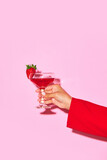 Fototapeta Sport - Female hand holding sweet cocktail with strawberry and coconut against pink background. Relaxation. Concept of alcohol and non-alcohol drink, party, holidays, bar, mix. Poster. Copy space for ad