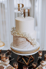 A wedding cake with the letters P and H on top. The cake is white and has a marble design