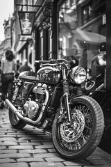 classic black and white photo of a motorcycle parked on the street. perfect for vintage or transport