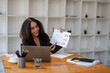 © Wasana - A woman is giving a presentation in front of a white wall. She is holding a piece of paper with graphs on it