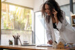 © Wasana - A woman in a white jacket is talking on her cell phone while sitting at a desk. Concept of productivity and focus, as the woman is engaged in a work-related activity. The presence of a laptop