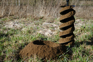 Drilling the ground with rig machine. The man drills the hole in land. Borering for the fence installation. Bore tool. Handy equipment. Portable manual earth auger for planting bushes and trees