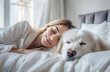 Young beautiful blonde caucasian woman and white labrador retriever dog sleeping together in bed.