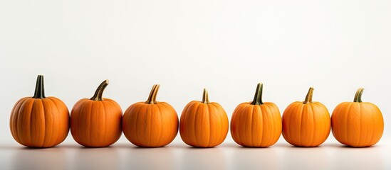 Poster - A bunch of identical orange pumpkins is displayed on a white background creating a Halloween themed copy space image