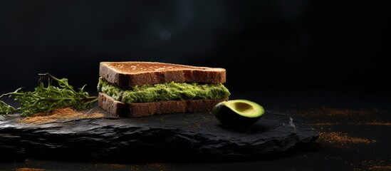 Wall Mural - A copy space image depicts toasted bread topped with fresh green avocado on a textured black surface