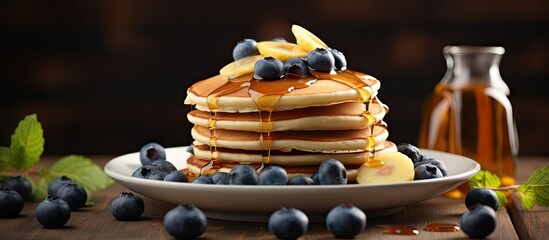 Aufkleber - A breakfast of fluffy pancakes topped with banana blueberries and maple syrup displayed on a wooden background with copy space
