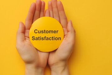 Customer review satisfaction feedback survey concept. Customer Satisfaction Badge. Close-up of two hands gently holding a yellow badge that reads 