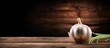 © vxnaghiyev - A copy space image of a fresh garlic bulb with a long stalk placed on a wooden table