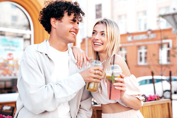 Sticker - Young smiling beautiful woman and her handsome boyfriend in casual summer clothes. Happy cheerful family. Female having fun. Couple posing in street. Holding and drinking cocktail drink in plastic cup