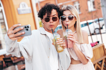 Sticker - Young smiling beautiful woman and her handsome boyfriend in casual summer clothes. Happy cheerful family. Female having fun. Couple posing in street. Holding and drinking cocktail drink in plastic cup