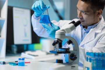 Scientist experimenting with chemicals in lab. Lab technician doing research on new chemicals in laboratory, adding solution in conical flask.