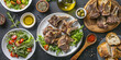 © Oleksandr - Table with lamb necks on an Arabic white plate, surrounded by bread and salad in small bowls, olive oil, olives, a bowl of green vegetables, a wooden spoon with spices.