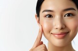 Fototapeta Sport - Chinese woman with clean and delicate skin, pointing to her cheek against a white background
