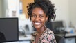 © JovialFox - Confident African American woman smiling proudly at her office desk, facing the camera with a computer nearby, generative ai