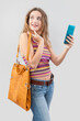 The smiling young woman, carrying a vintage leather bag, wears fashionable clothes while browsing an internet web page or online store and utilizing her smartphone for online shopping or social media
