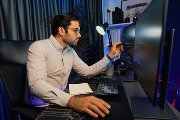 Working smart IT developer pointing data software development on two pc screen, creating application program updated version online website page system online at neon light cyber office. Surmise.