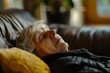 An elderly Caucasian woman takes a peaceful nap on a cozy couch in a sunlit living room, showcasing a moment of rest and tranquility.