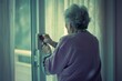 An elderly woman in a lavender sweater adjusts a wall thermostat beside a curtained window, depicting everyday domestic life and senior living.