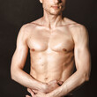 © vladorlov - A man with a beautiful body poses in the studio against a black background.