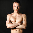 © vladorlov - A man with a beautiful body poses in the studio against a black background.