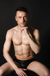© vladorlov - A man with a beautiful body poses in the studio against a black background.