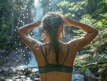 Woman Washing Hair Under Waterfall In Forest