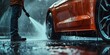 A man stands next to a red car in the rain, his silhouette visible against the wet backdrop as drops fall around him