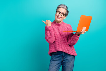 Wall Mural - Photo of pleasant smart person in glasses hold laptop directing look at interesting offer empty space isolated on teal color background