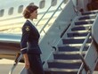 © Veronika - Professional female flight attendant standing at the airplane's steps