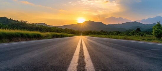 An empty asphalt road leading into the distance, with mountains in the background