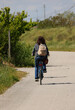 woman with a backpack on their shoulders pedaling leisurely on the cycle path in the countryside