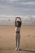 Fit black woman doing relaxation and breathing exercise at the beach. Fitness and yoga relax outdoor. Stretching arms.