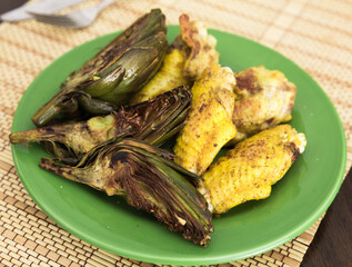 Wall Mural - Cooked fried chicken wings and halves artichokes on green plate