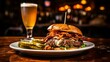 A delicious burger with bacon and cheese served with a glass of beer and pickles on the side