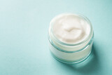 Fototapeta  - Cream jar on blue background. Skin care product. Close up.