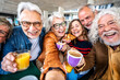 Happy senior people taking selfie picture sitting at cafe bar table - Older friends having breakfast together drinking coffee and fruit juice outdoors - Food and beverage lifestyle concept