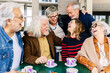 Joyful group of senior friends having fun drinking coffee at cafeteria bar. Baby boomer generation people laughing bonding while having breakfast together at coffee shop. Elderly lifestyle concept.